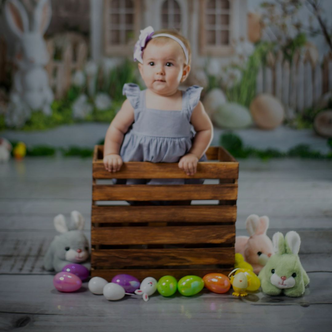 Cute baby sitting in toy setup with wooden box
